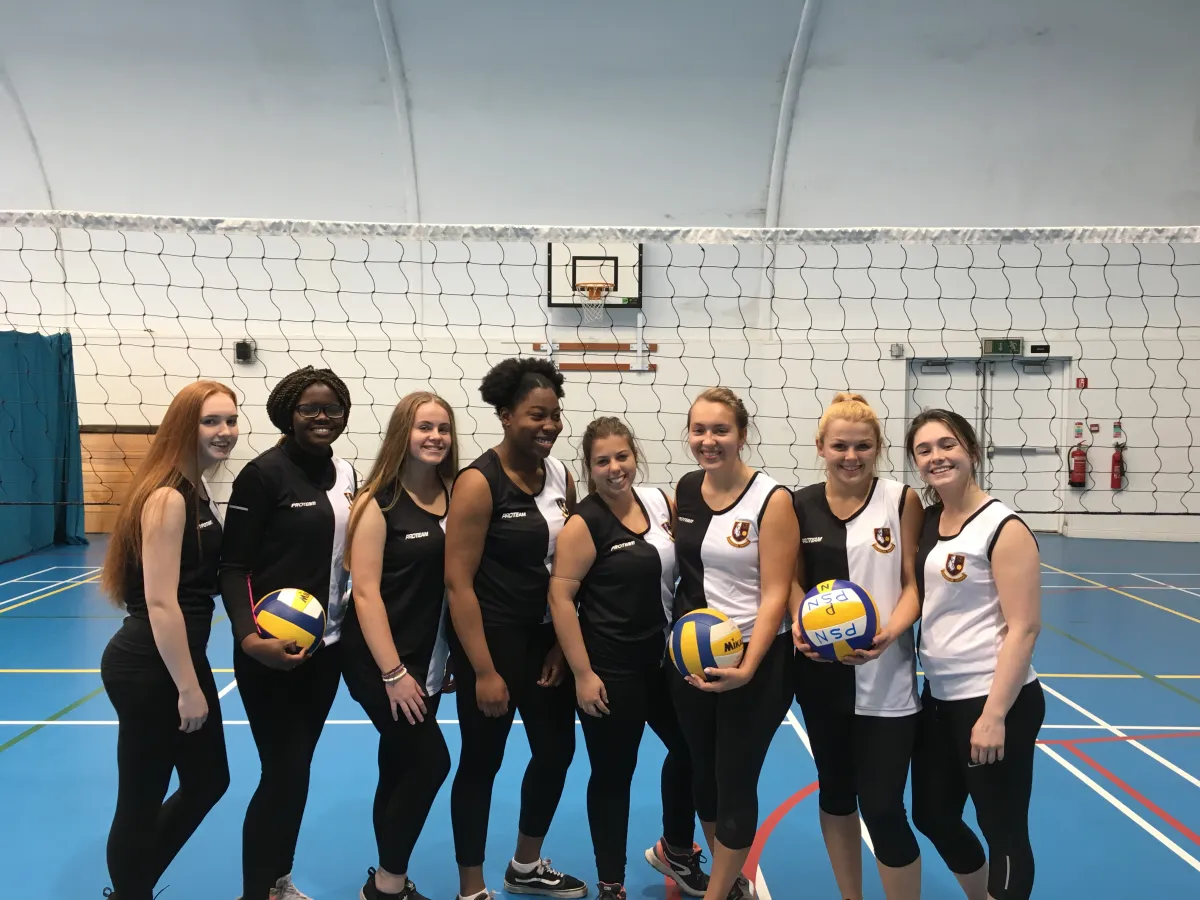 Gruppe Volleyballspielerinnen in Sporthalle vor Netz