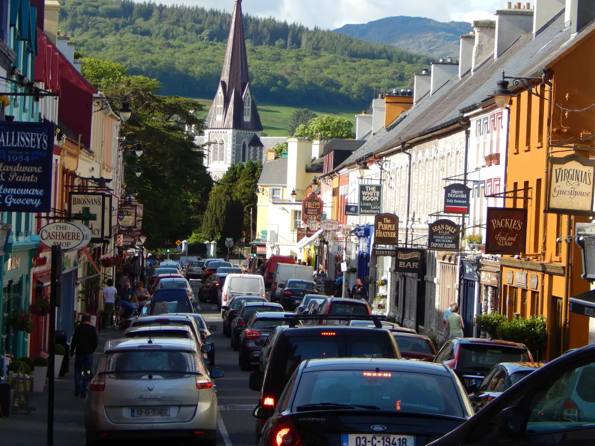 Strasse mit Autos auf Kirchenturm zu durch Ortschaft in Irland
