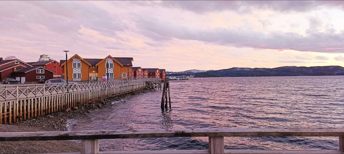 Pier mit Häusern in einem norwegischen Fjord während Sonnenuntergang
