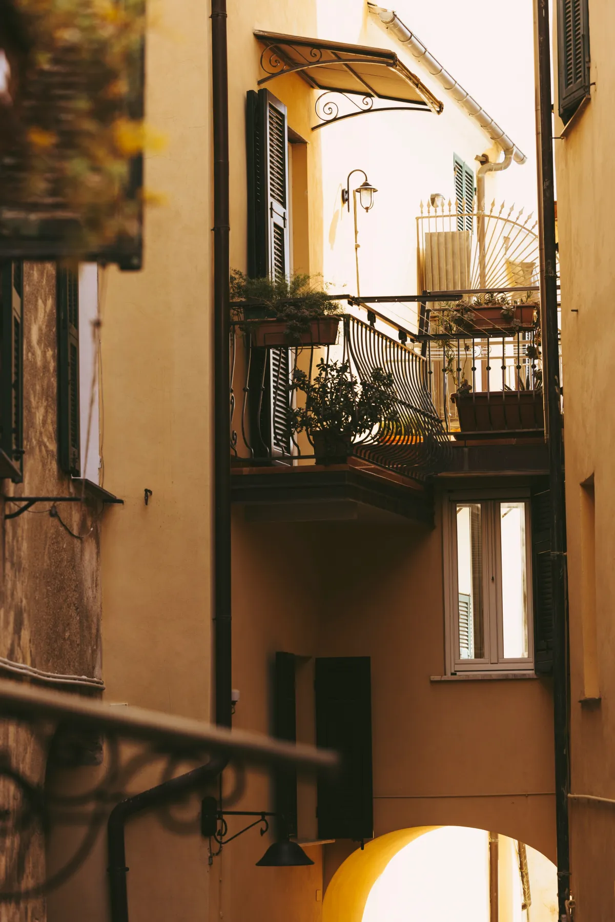 Gelbes Haus im Schattenspiel in Gasse mit romantischem Balkon