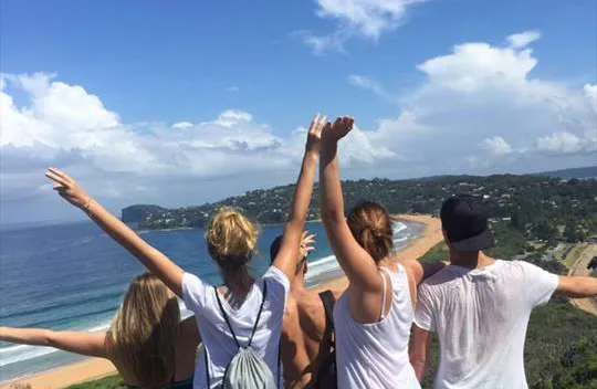 Austauschschüler von hinten jubelnd mit Aussicht über Strand und Meer in Australien Bucht