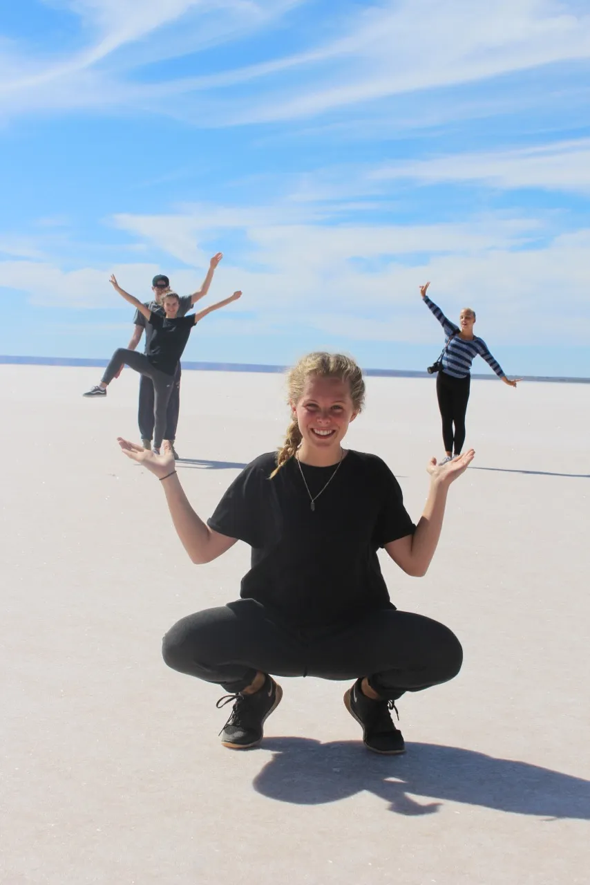 Schüler in schwarzen Kleidern in weisser Sandwüst mit blauem Himmel in Australien