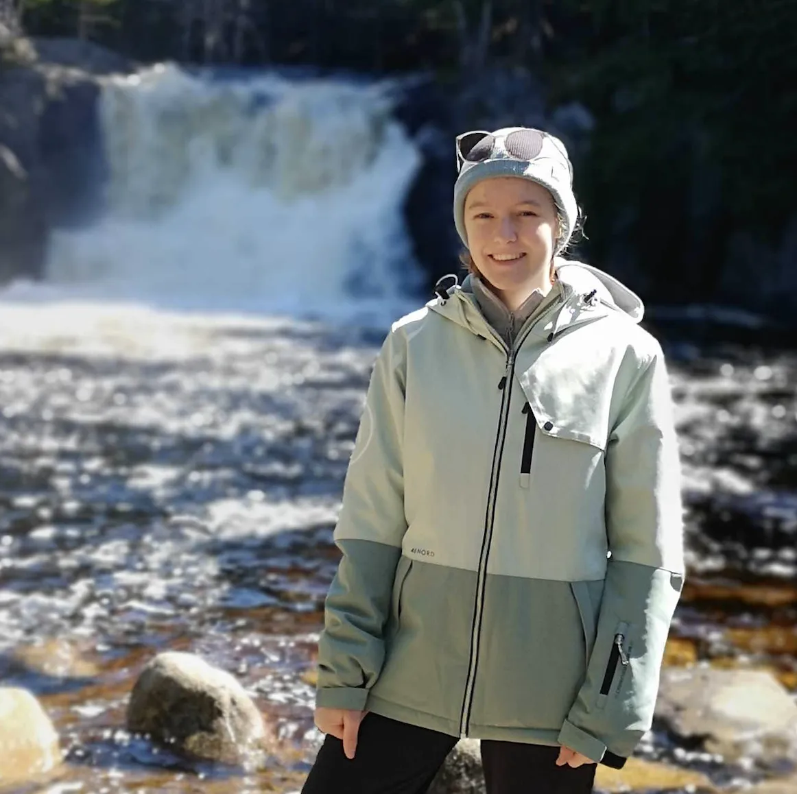 Mädchen steht vor einem Wasserfall im Winter