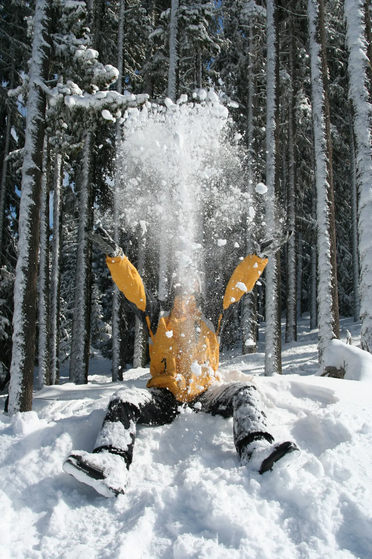 Eine Person sitzt auf einem Schneehaufen und wirft Schnee