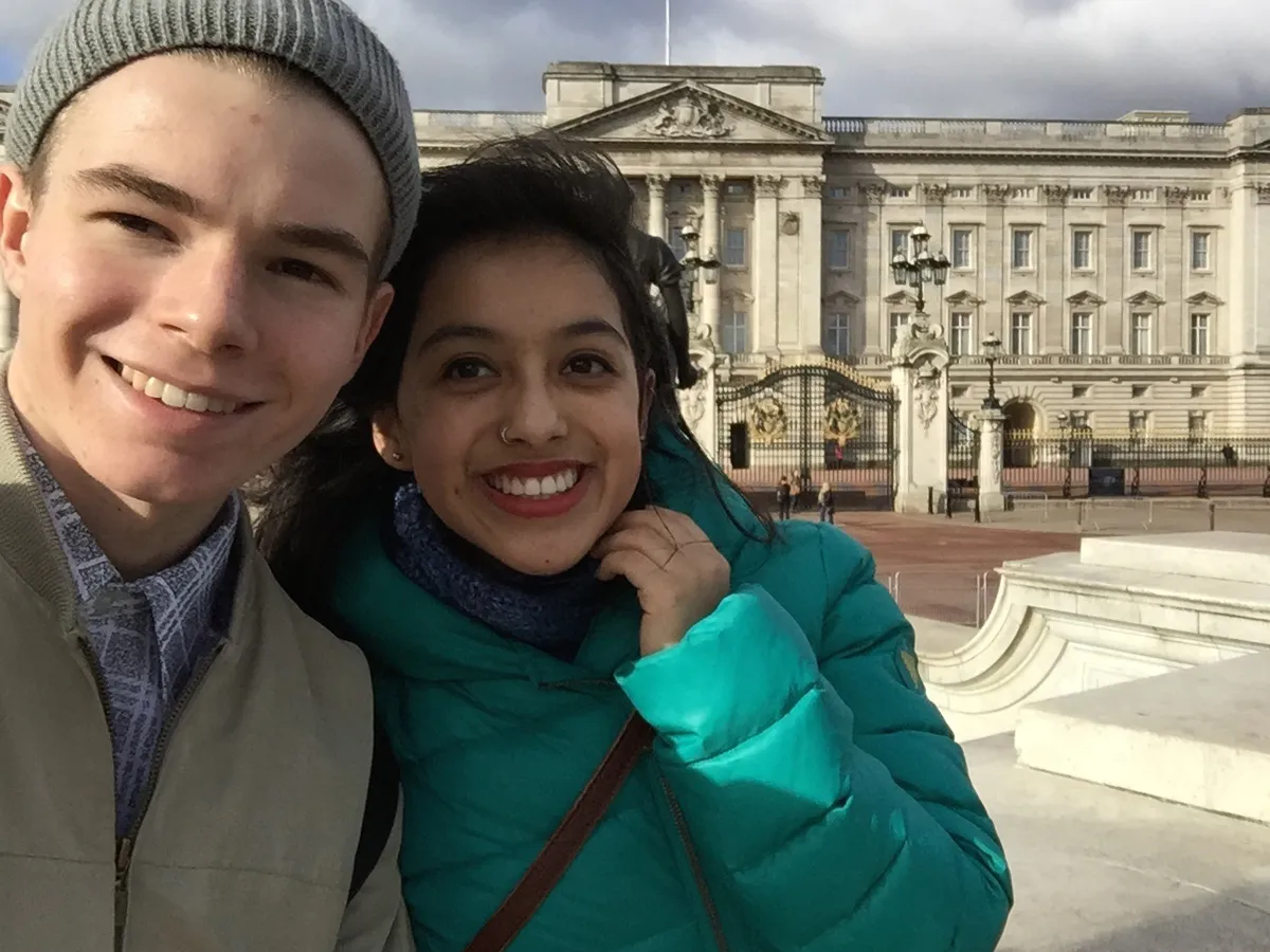 Junge und Mädchen posieren lachend vor englischem Palast