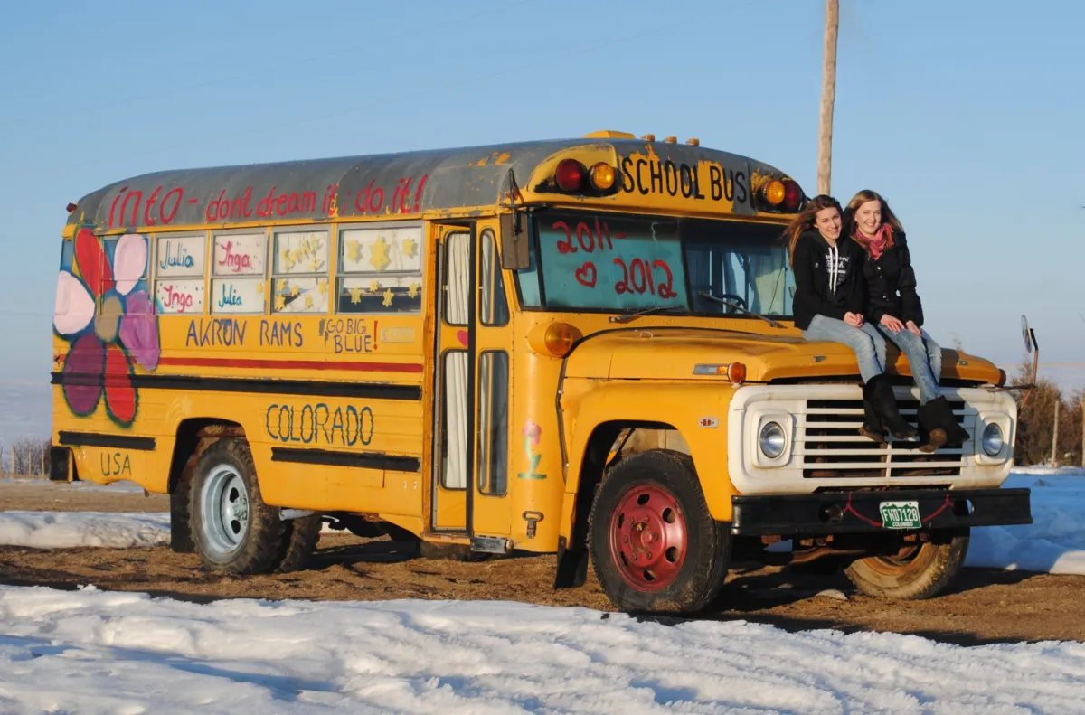 Gelber Amerikanischer Schulbus mit zwei Frauen auf der Haube
