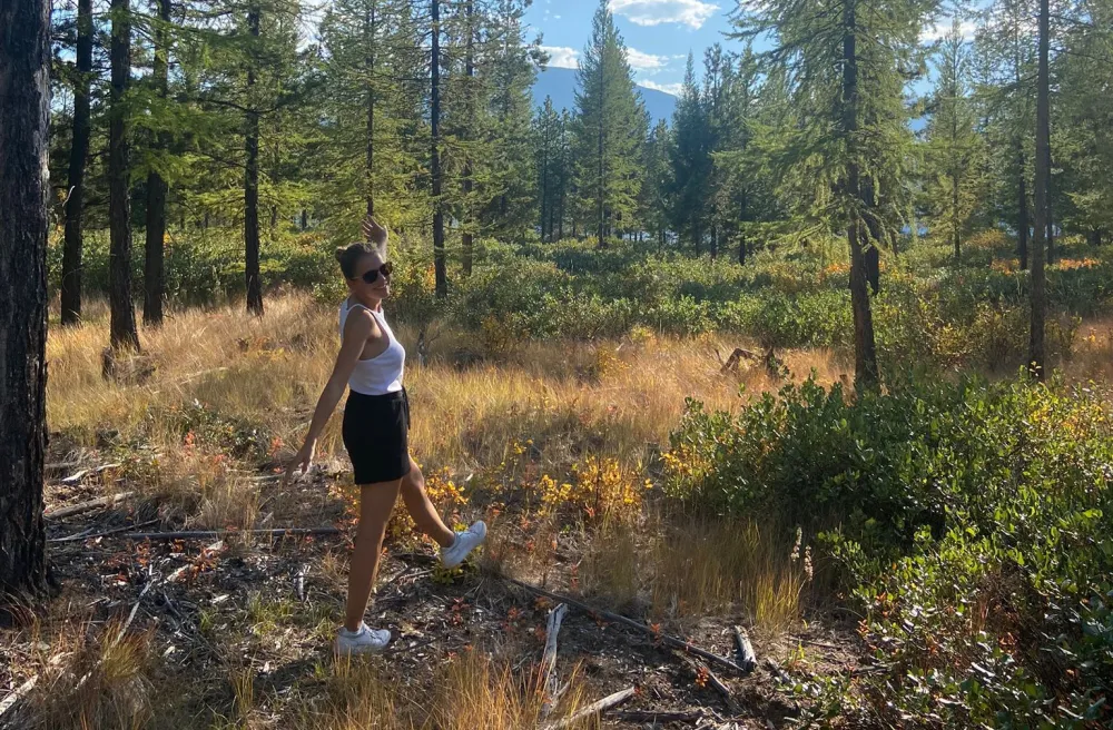 Schülerin steht in einer Waldlichtung an einem Sommertag