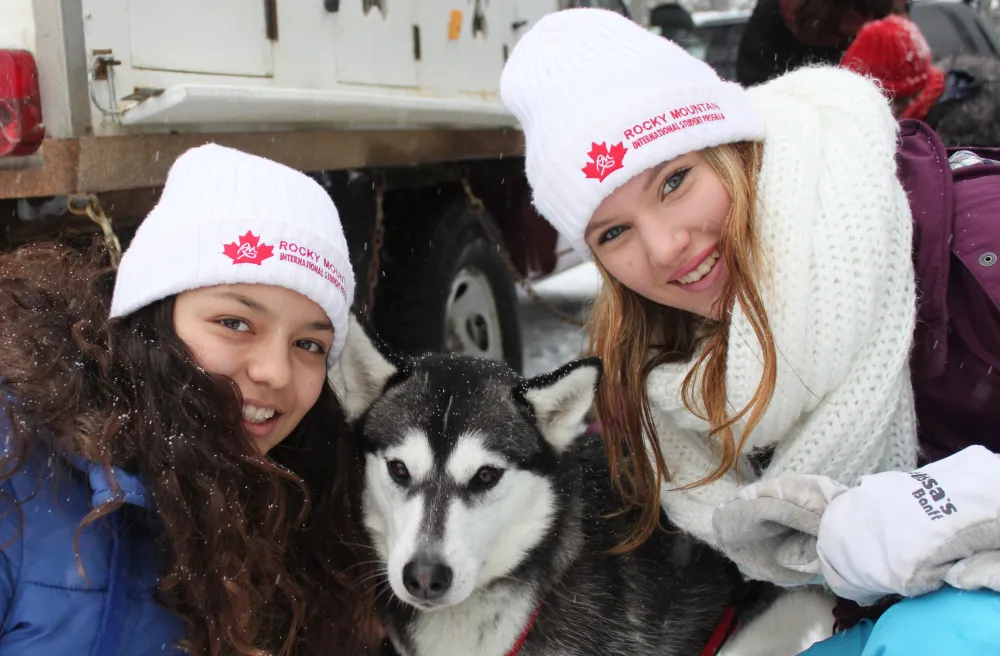 Zwei Mädchen mit Husky in Mützen in Winterlandschaft