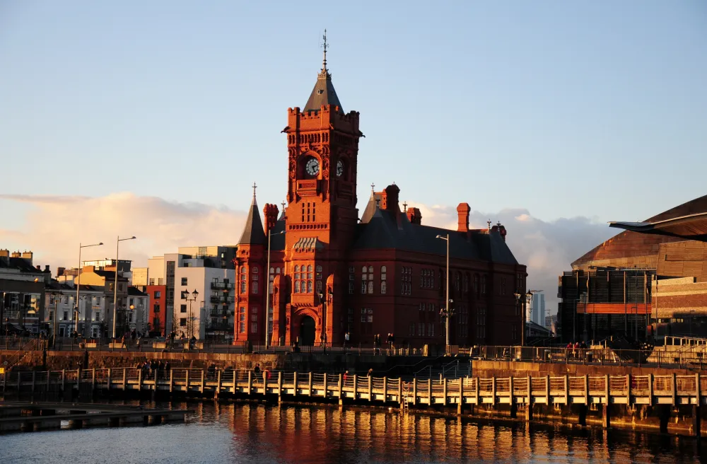 Grosse, rote Kirche in England im Abendlicht neben Wasser