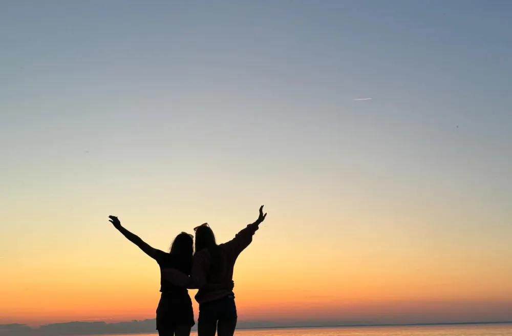Freunde umarmen sich und schauen den Sonnenuntergang am Strand