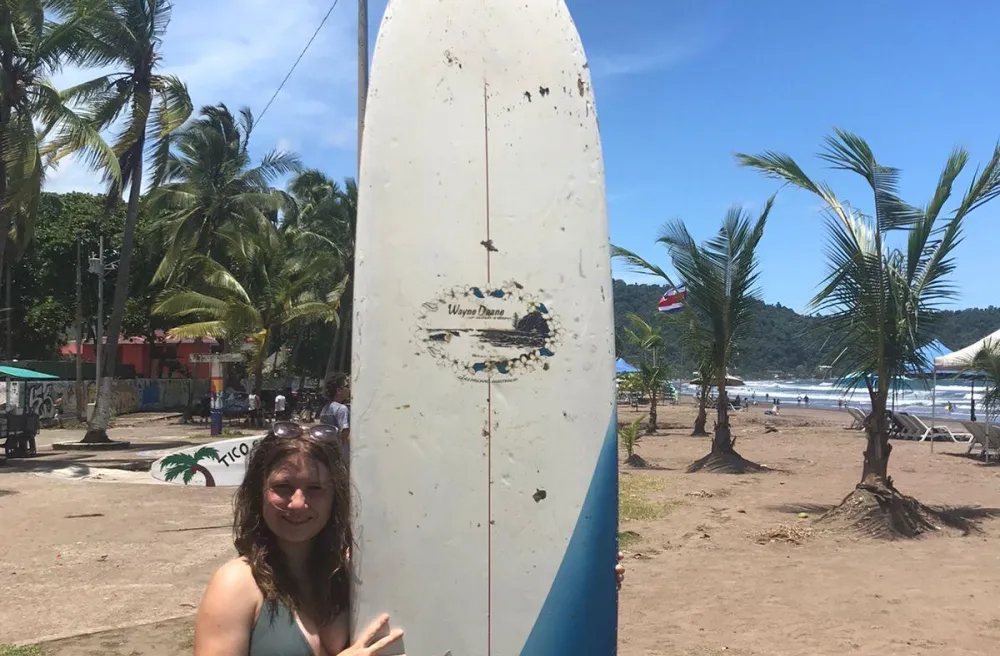 Costa Rica Austauschschülerin mit Surfboard in der Hand am Strand