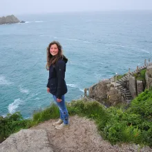 Mädchen steht auf Aussichtspunkt hoch über dem Atlantik in Jacke