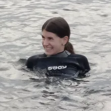 Schülerin im Neoprenanzug, Schwimmen im Meer, lachend, Baden