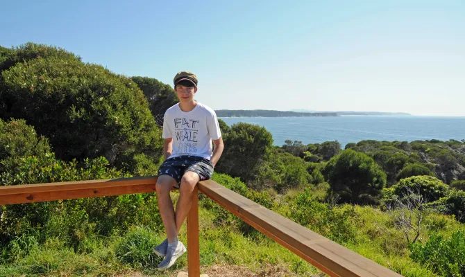 Austauschschüler sitzt an der australischen Küste bei einem Aussichtspunkt.