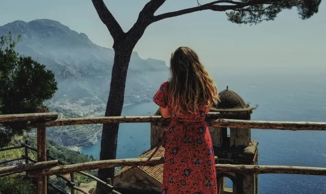 Schülerin in rotem Sommerkleid aus Aussichtspunkt über italienischer Riviera