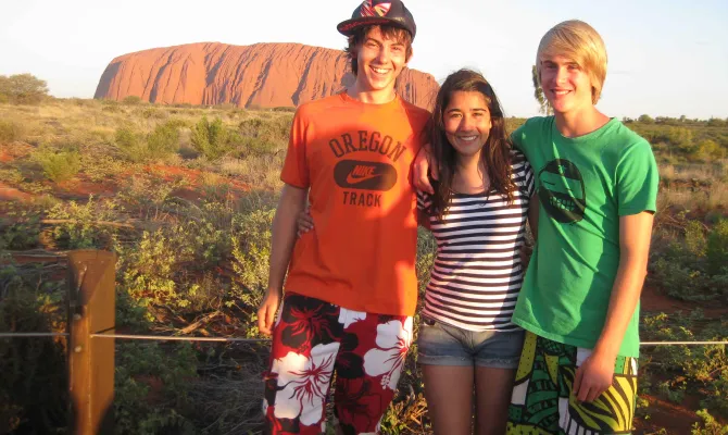 Drei Teenager stehen vor dem Eyers Rock in Australien