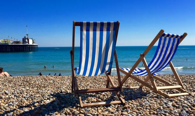 Blau weisse Liegestühle an südländischem Steinstrand bei blauem Himmel