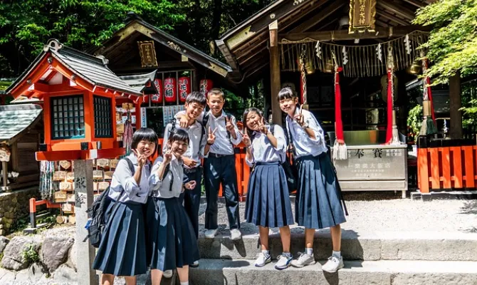 Japanische Schüler:innen vor Tempel unter Bäumen