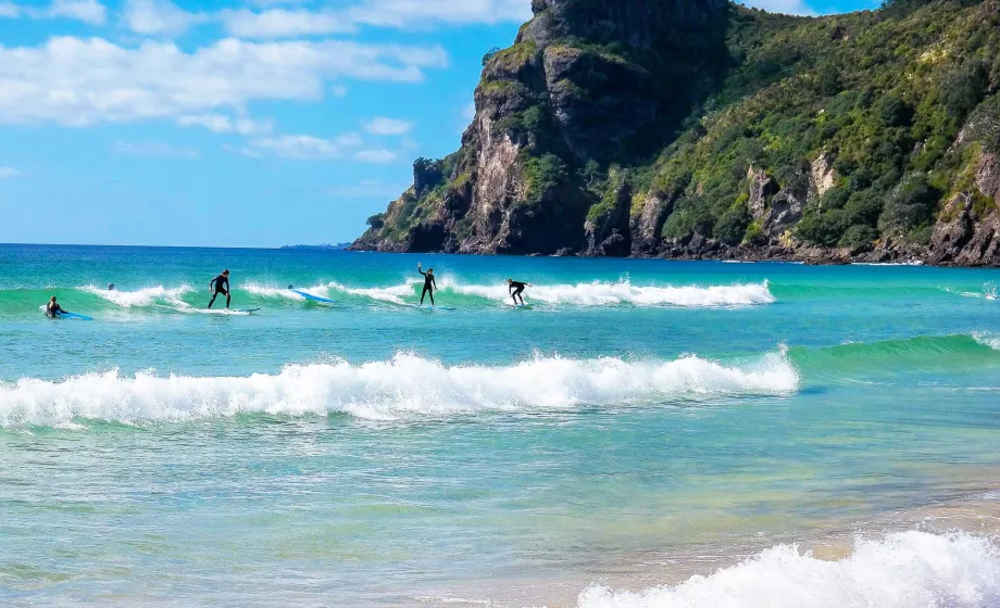 Gruppe von Austauschschüler surfen in Neuseeland an atemberaubendem Beach.