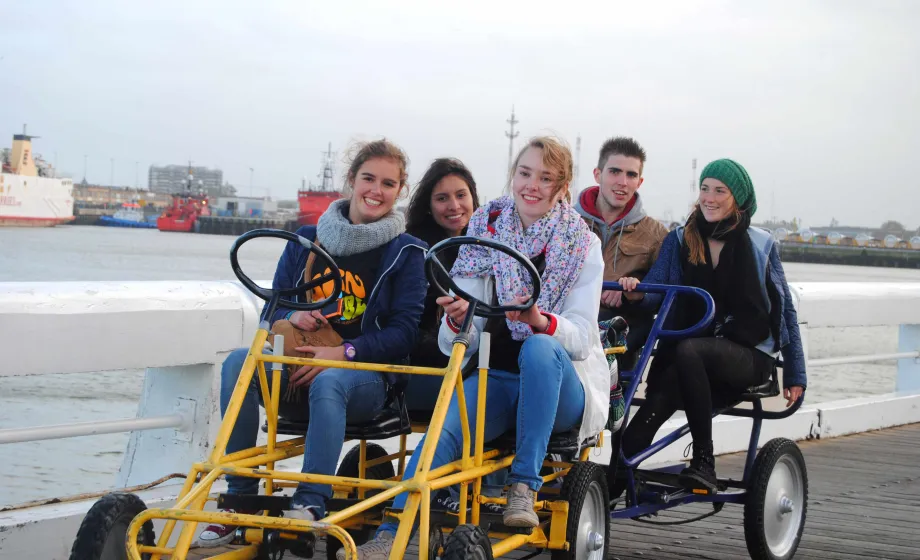 Austauschschüler:innen auf Cityentdeckungstour mit Fünfplätzer-Fahrrad. 