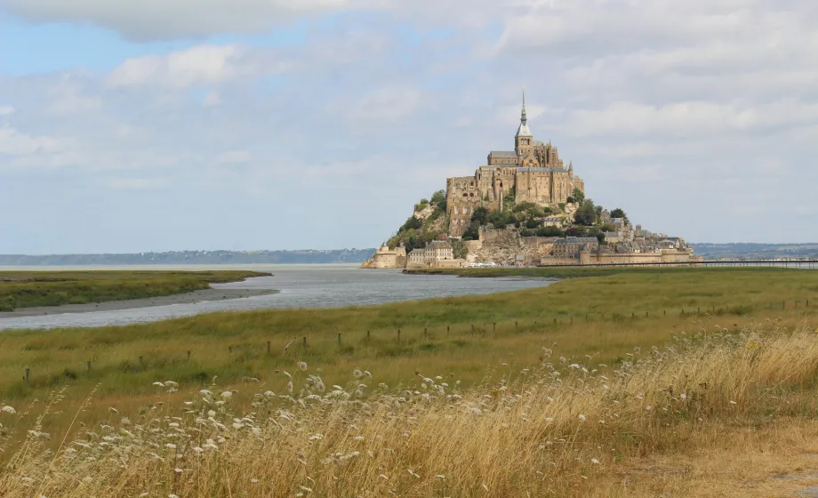 Burg auf Insel im Meer an Küste mit Dünen und Schilf im Vordergrund