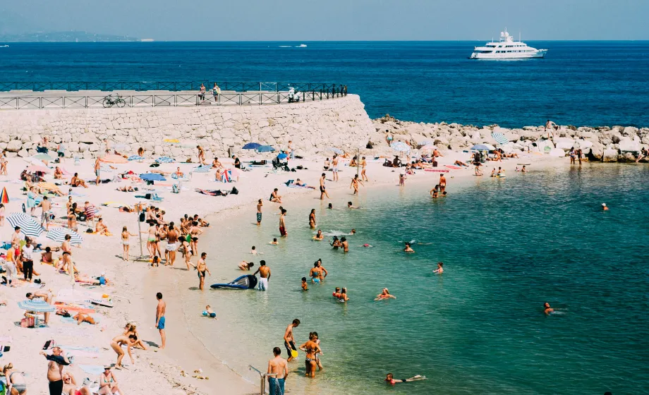 Weisser Badestrand mit vielen Leuten am Beach und im Wasser