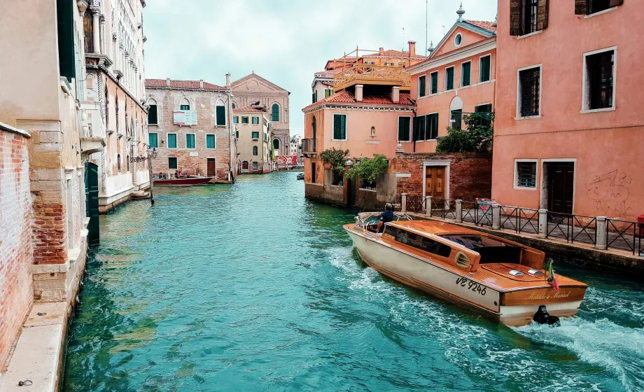 Boot auf Kanal in Venedig entlang terracotafarbenen Häuser