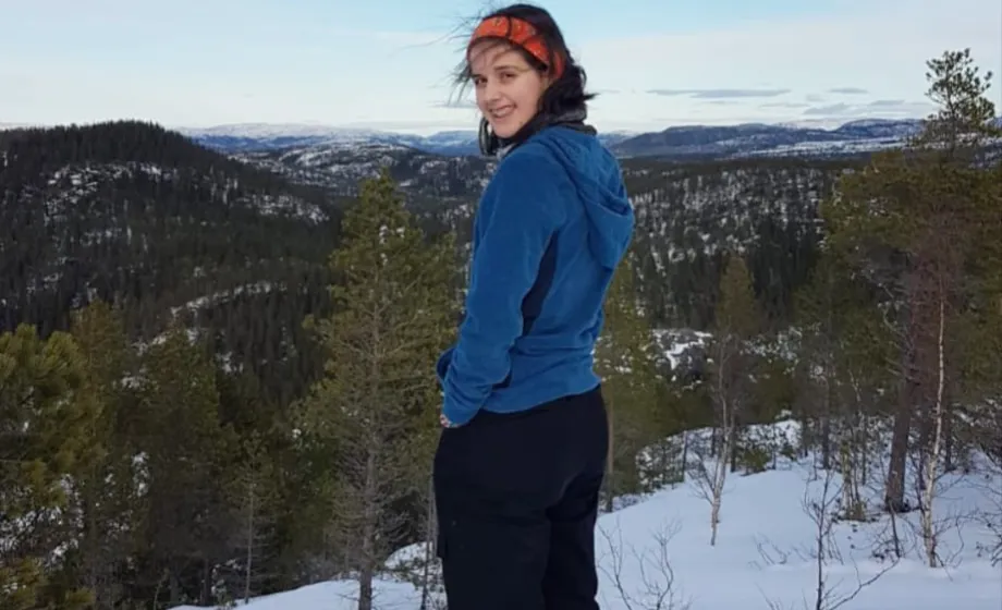 Mädchen schaut zurück und lächelt in Kamera steht in Schnee im winterlichen Norwegen 