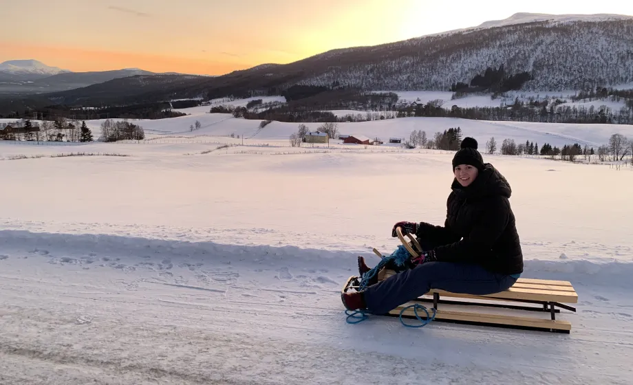 Junge auf Schlitten in Norwegen während Sonnenuntergang