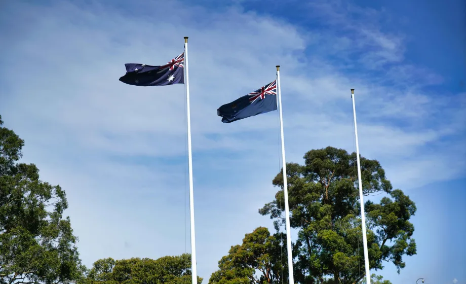Australische Flaggen wehend über Bäumen in blauem Himmel