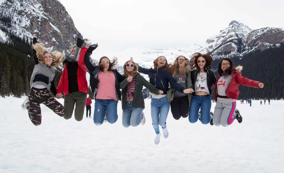 Schülerinnen springen vor Freude in die Luft über verschneitem See