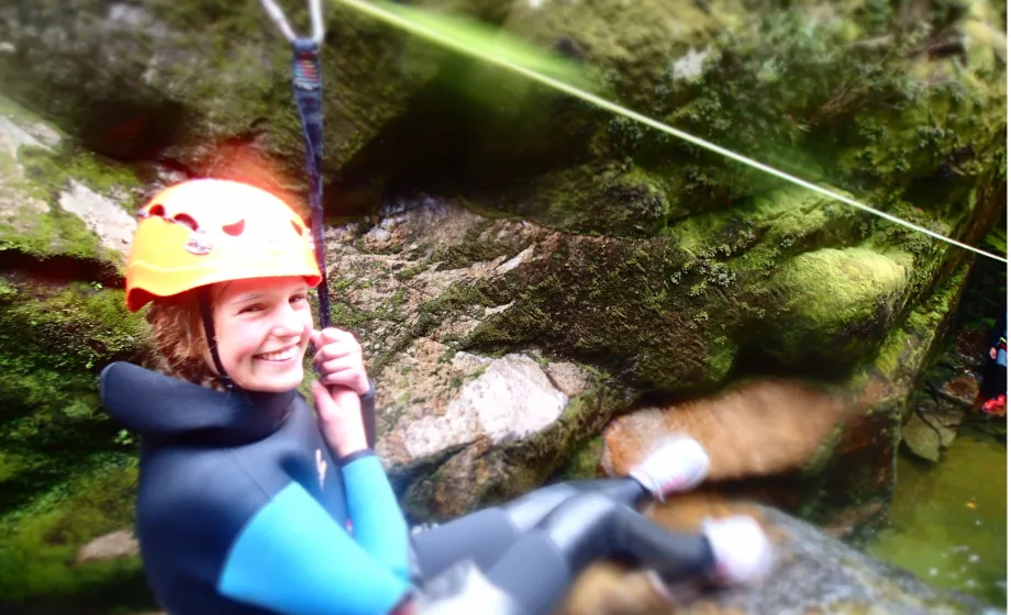 Maedchen mit Helm auf Zipline in Canyon