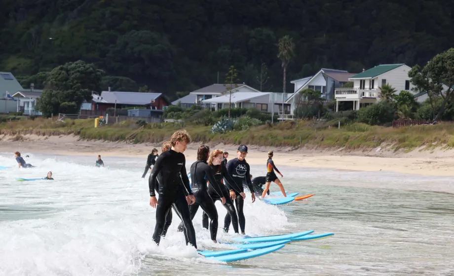 Surfergruppe im Wasser in einer Linie auf Longboards