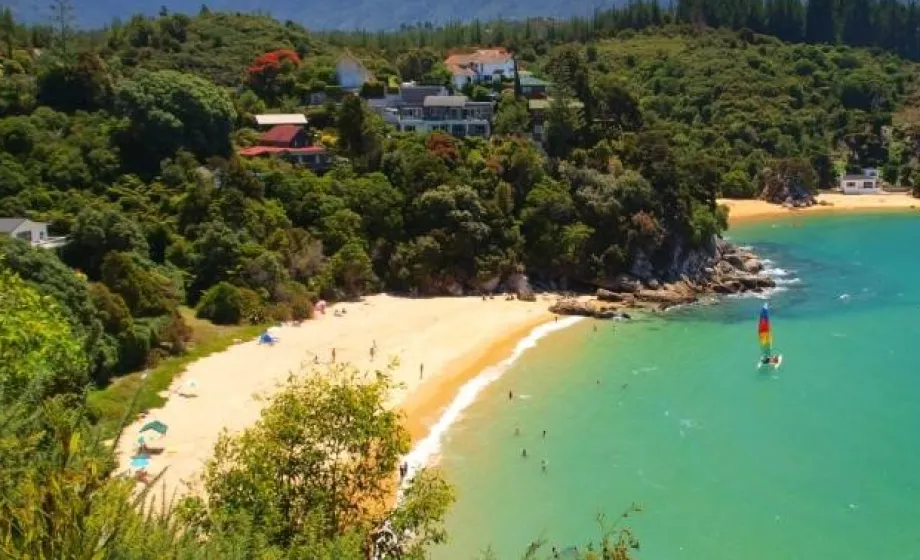 Weisser Sandstrand in Bucht mit türkisfarbigem Meer und Bäumen