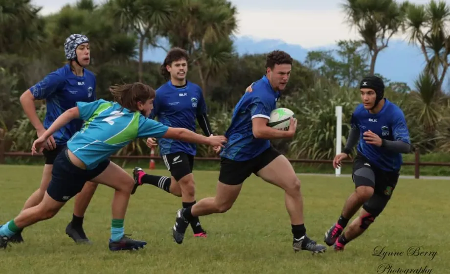 Rugbyteam in blauem Tenue auf Rasen am laufen