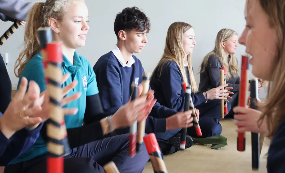 Schüler lernen traditionelles Handwerk von Maoris mit Stäben