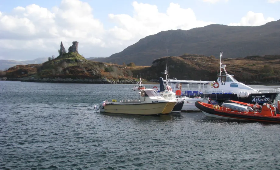 Boote im Wasser vor Insel mit Schloss in Schottland