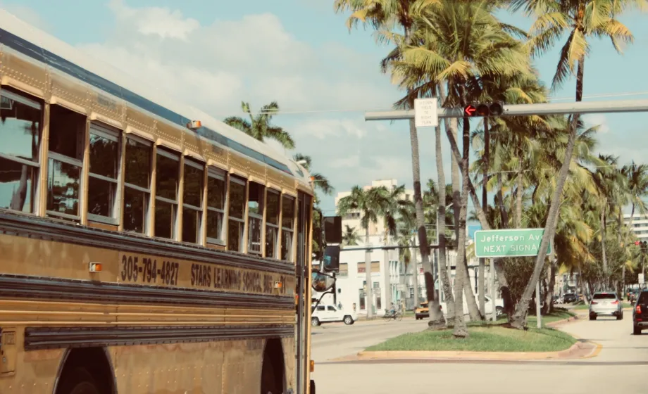 Gelber Schubus fährt durch Florida mit Palmen in Sommerwetter