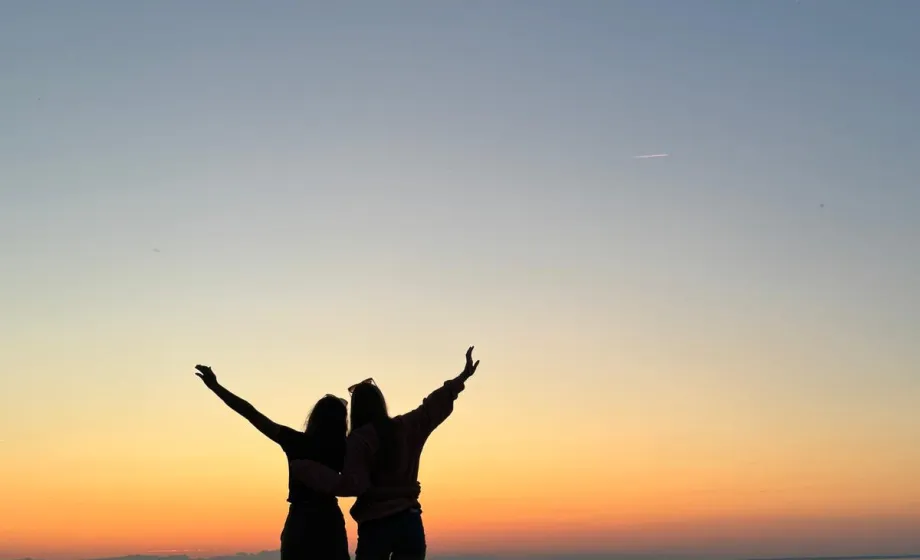 Freunde umarmen sich und schauen den Sonnenuntergang am Strand