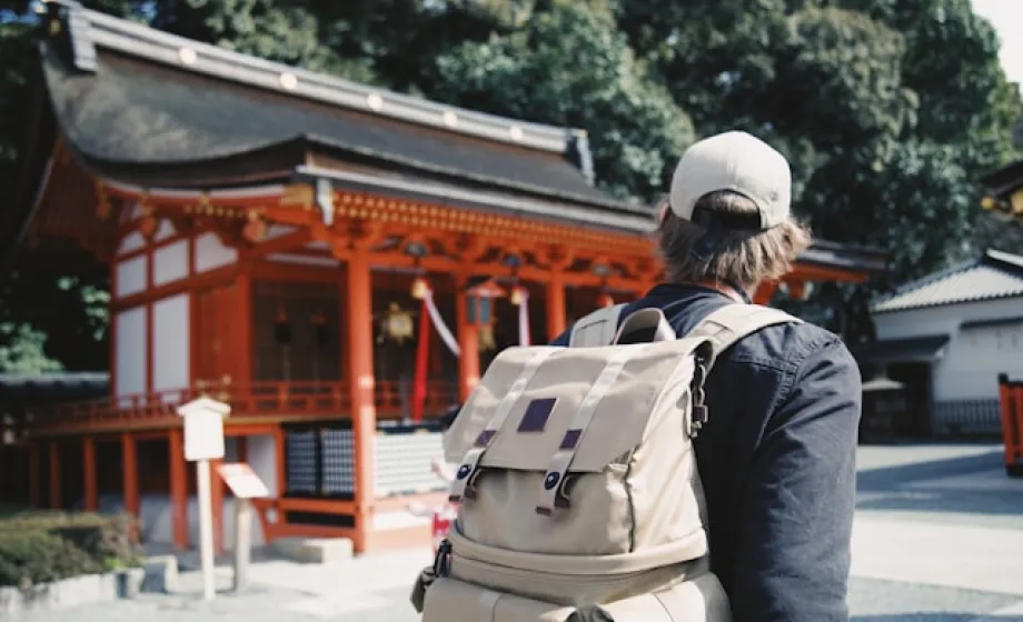 Tourist mit Rucksack geht an japanischem Tempel vorbei