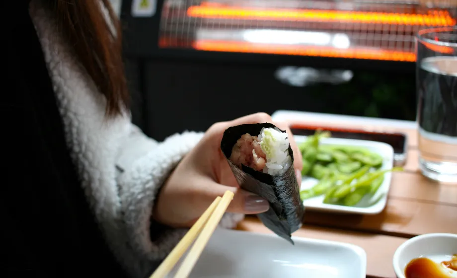 Selbstgemachte Sushirolle in der Hand mit Jobsticks