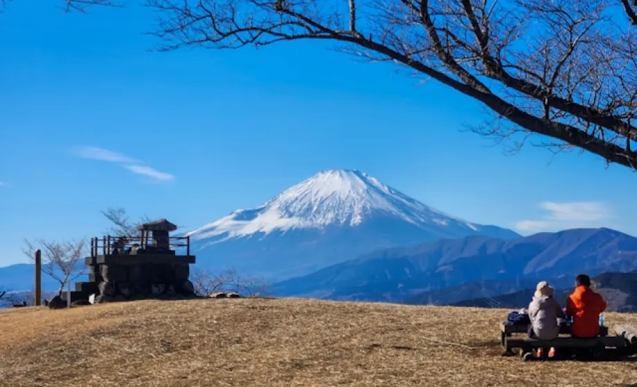 Menschen auf Bank geniessen Ausblick auf Vulkan auf Hügel in Japan